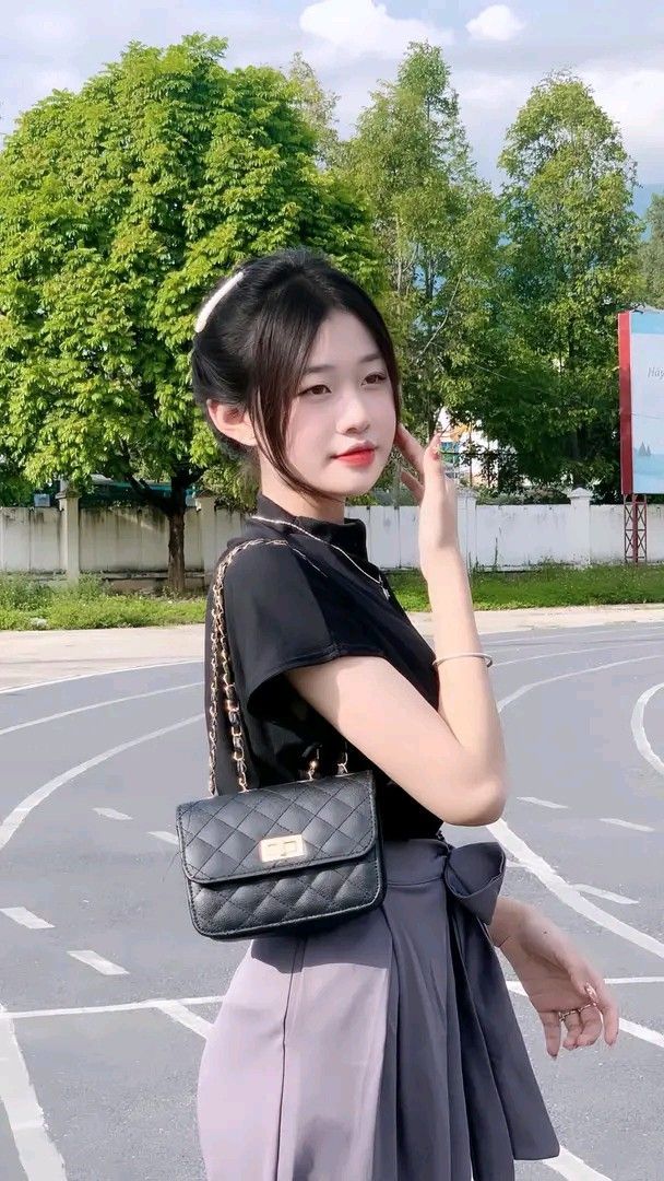 Cô gái trẻ mặc áo phông đen và chân váy xám giữa phố