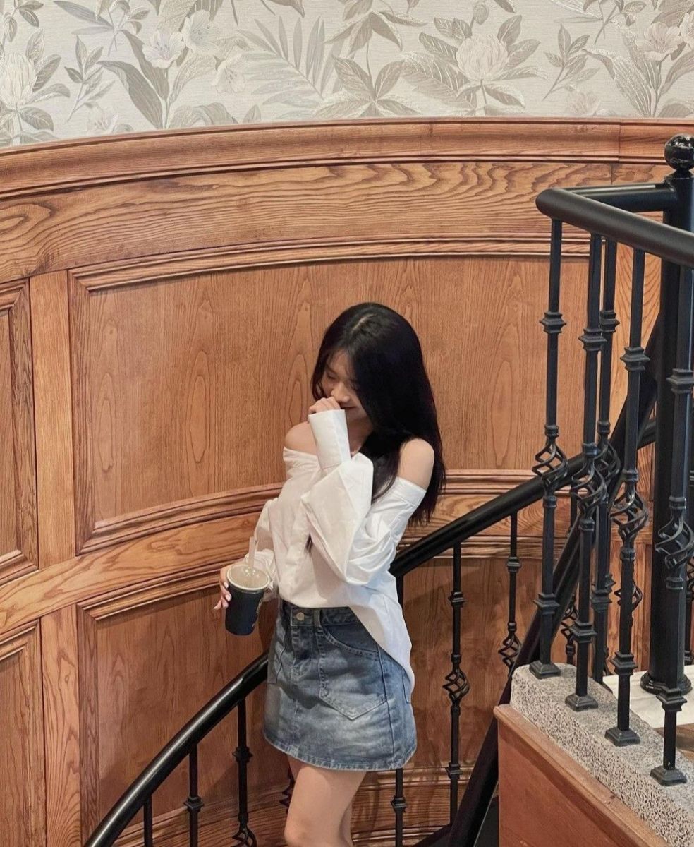 Cô gái trẻ mặc áo sơ mi trắng và váy jeans ngắn