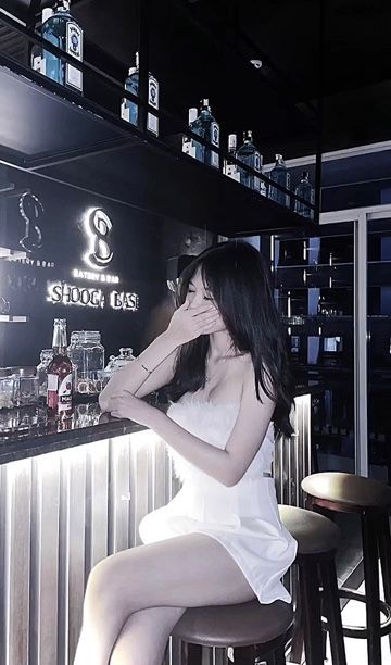 Cô gái trẻ mặc váy trắng tại quầy bar