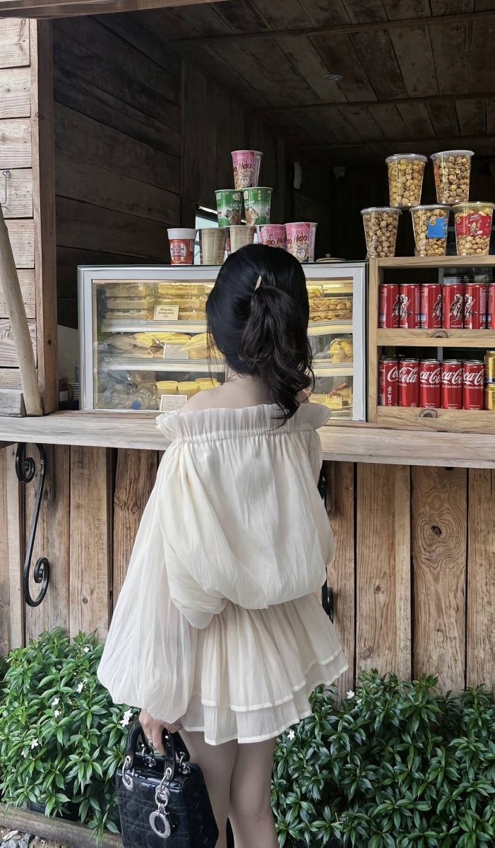 Cô gái trẻ xinh đẹp mặc áo blouse trắng trước quầy bán đồ ăn