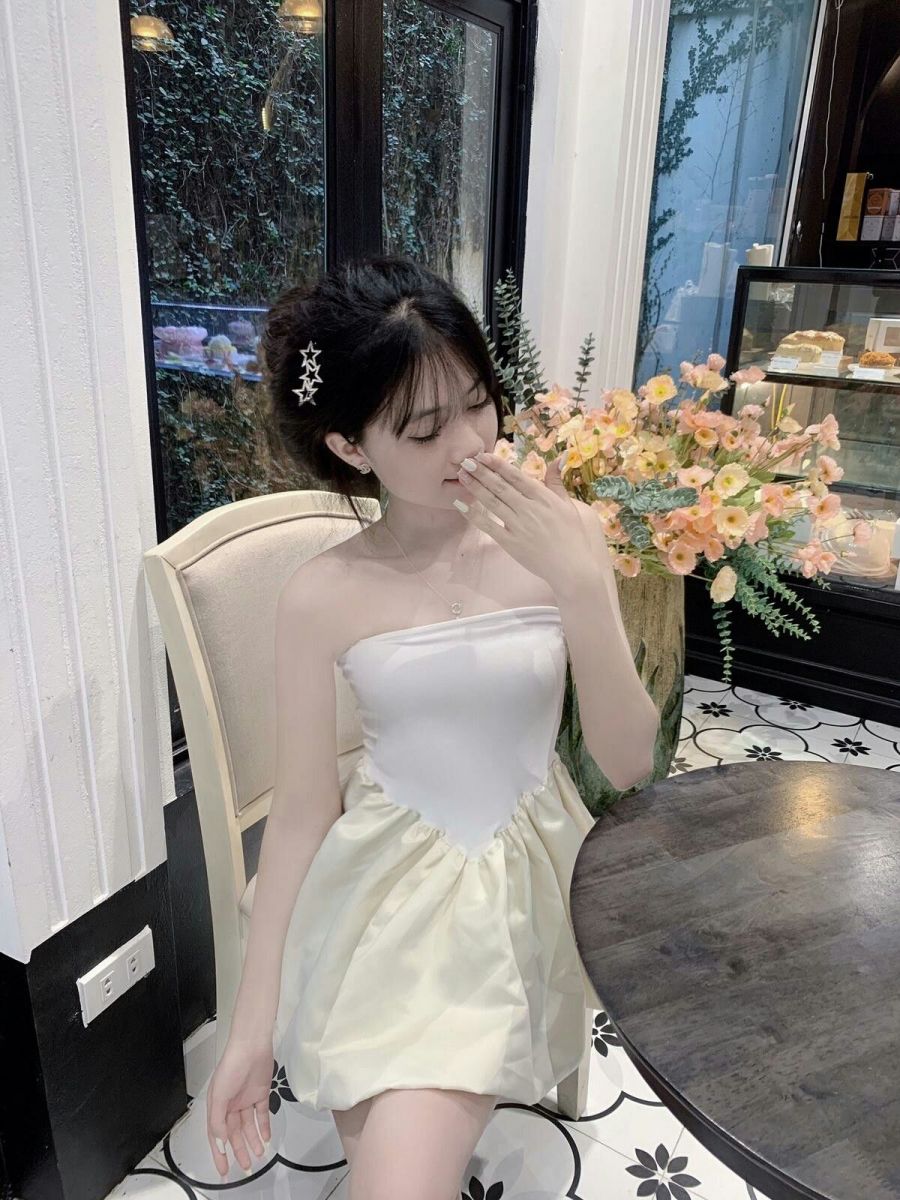 Cô gái trẻ xinh đẹp trong quán cà phê với váy trắng và vàng