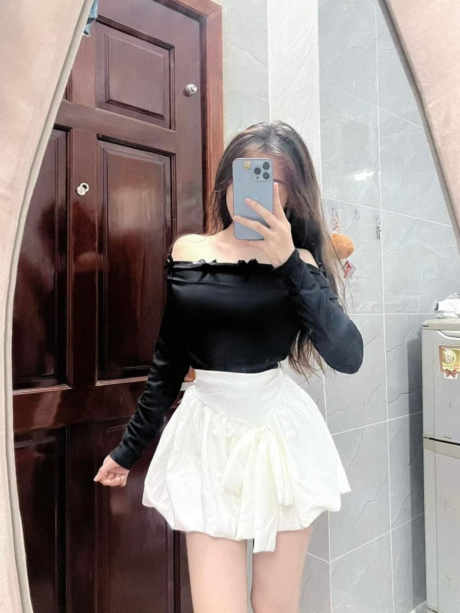 Cô gái trong áo dài tay màu đen và chân váy trắng chụp ảnh tự tin