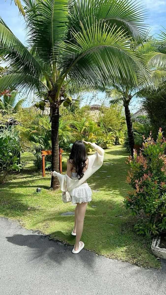 Cô gái xinh đẹp trong áo khoác nhẹ và váy trắng giữa khu vườn xanh mát