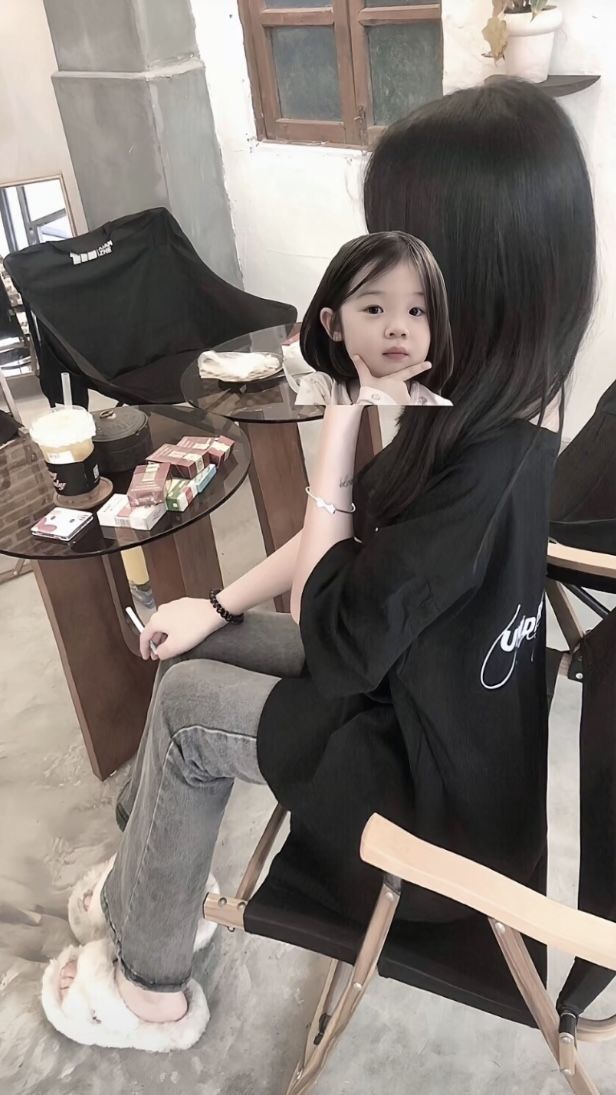 Cô gái xinh mặc áo phông đen và quần jeans ngồi trên ghế gỗ