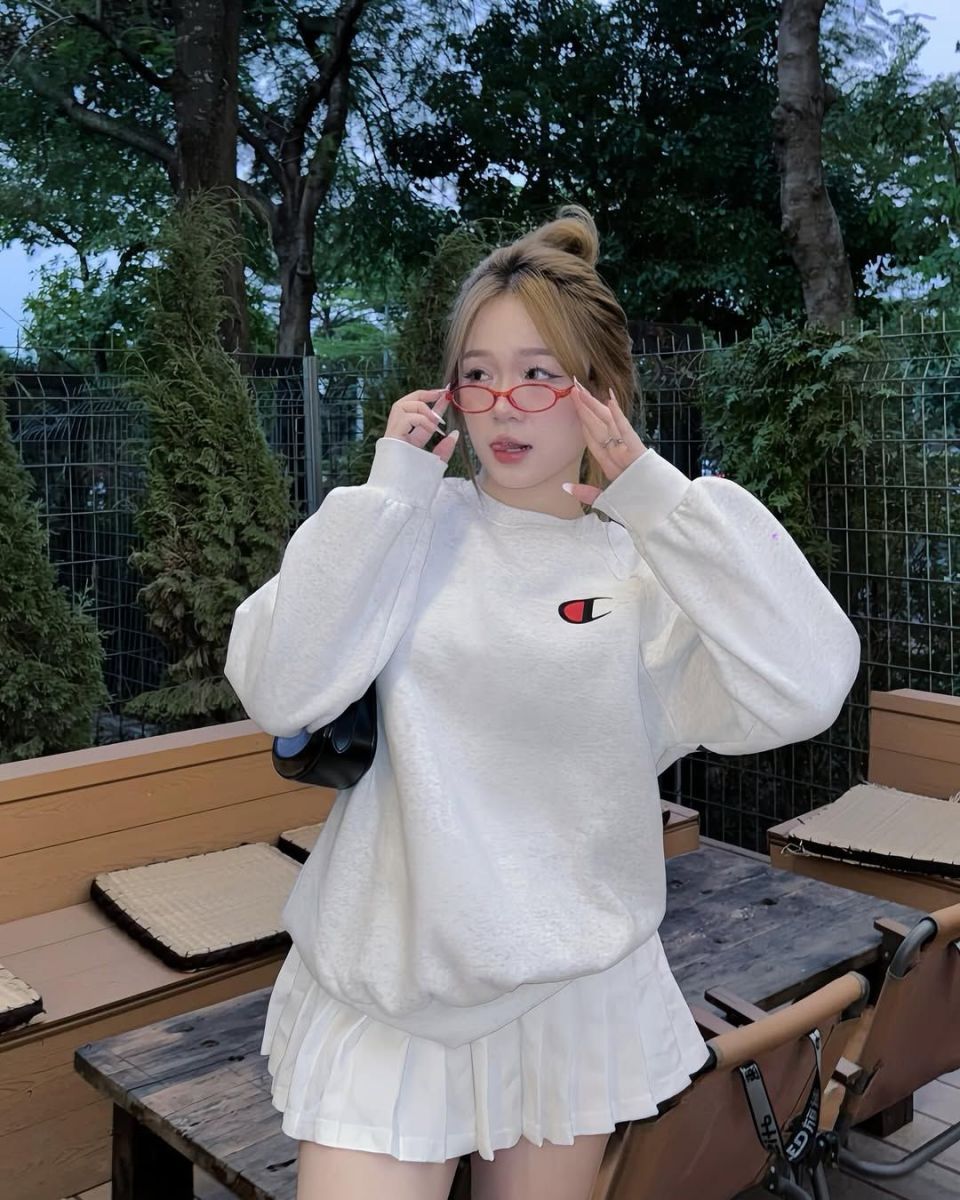 Cô gái xinh mặc áo sweatshirt trắng và váy xếp ly