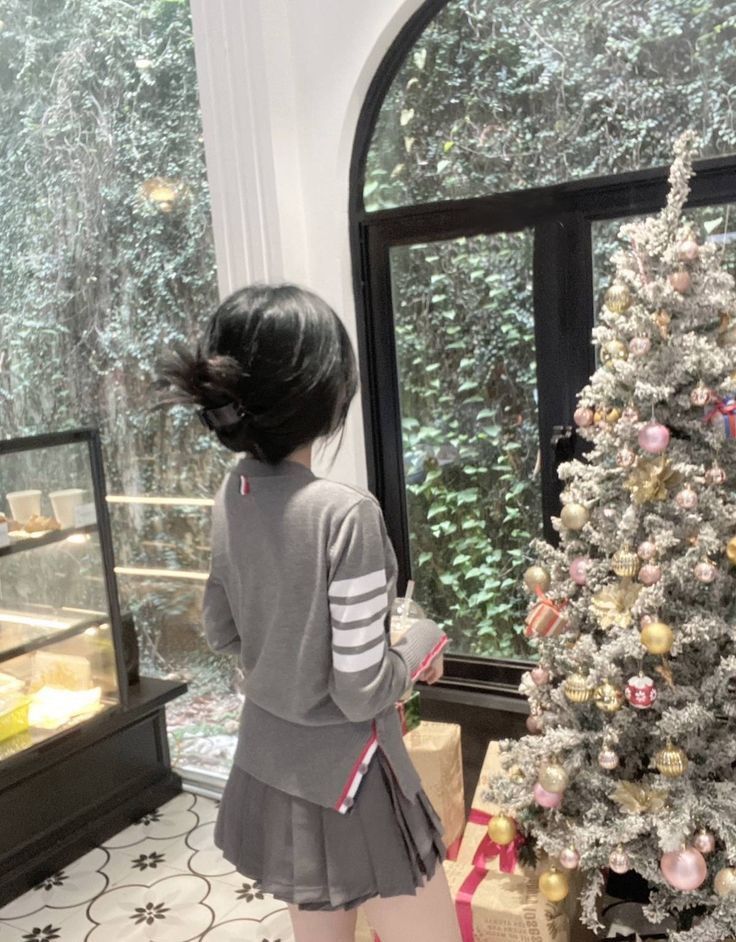 Gái xinh diện áo len xám và chân váy xếp ly bên cây thông Noel