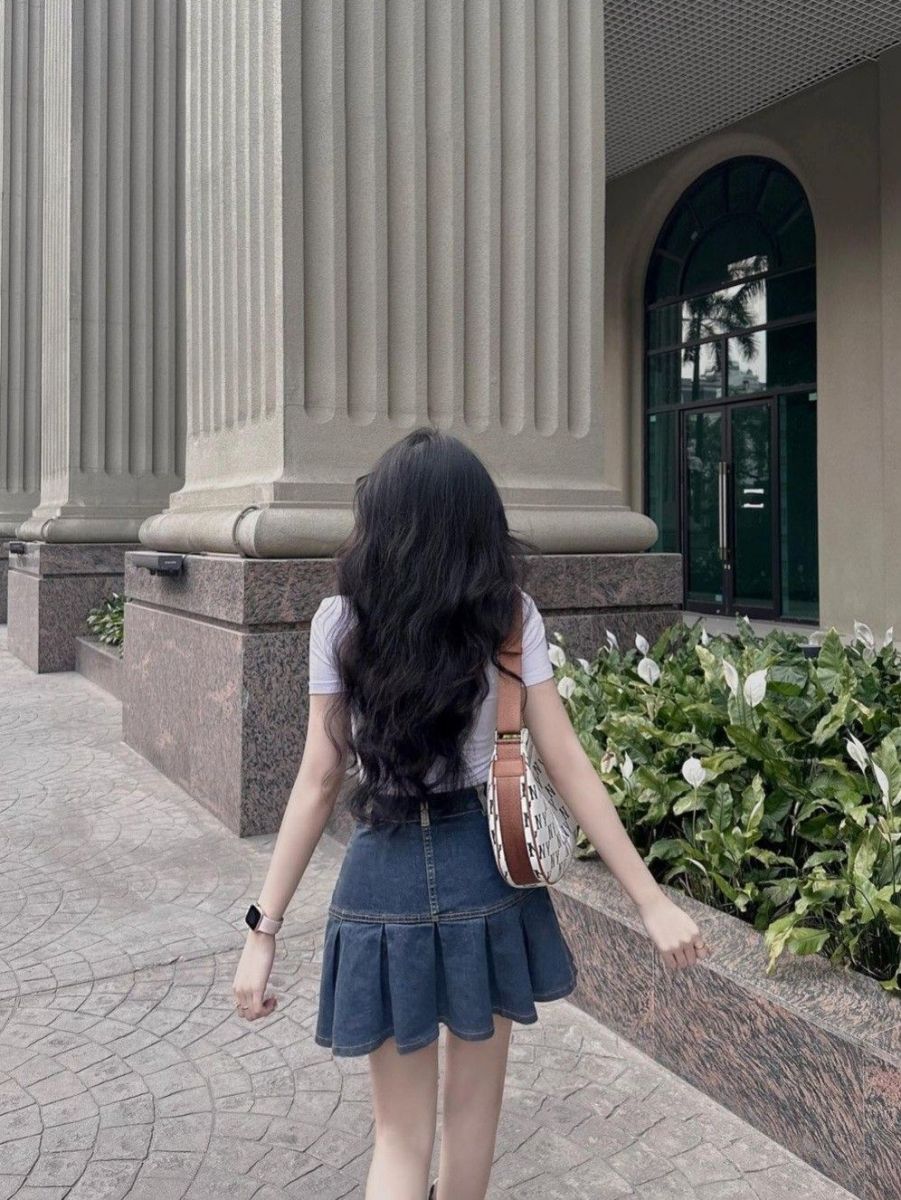 Gái xinh mặc áo thun trắng và chân váy jeans đi bộ nhẹ nhàng