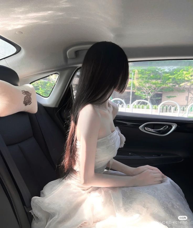 Gái xinh mặc váy trắng ngồi trong xe ô tô nhìn ra ngoài