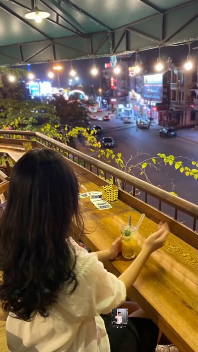 Gái xinh trong áo trắng ngồi nhâm nhi đồ uống trên ban công