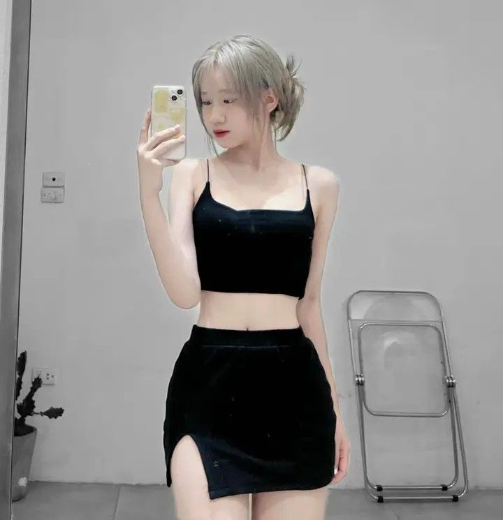 Ảnh gái trẻ mặc áo crop top đen và chân váy ngắn chụp selfie