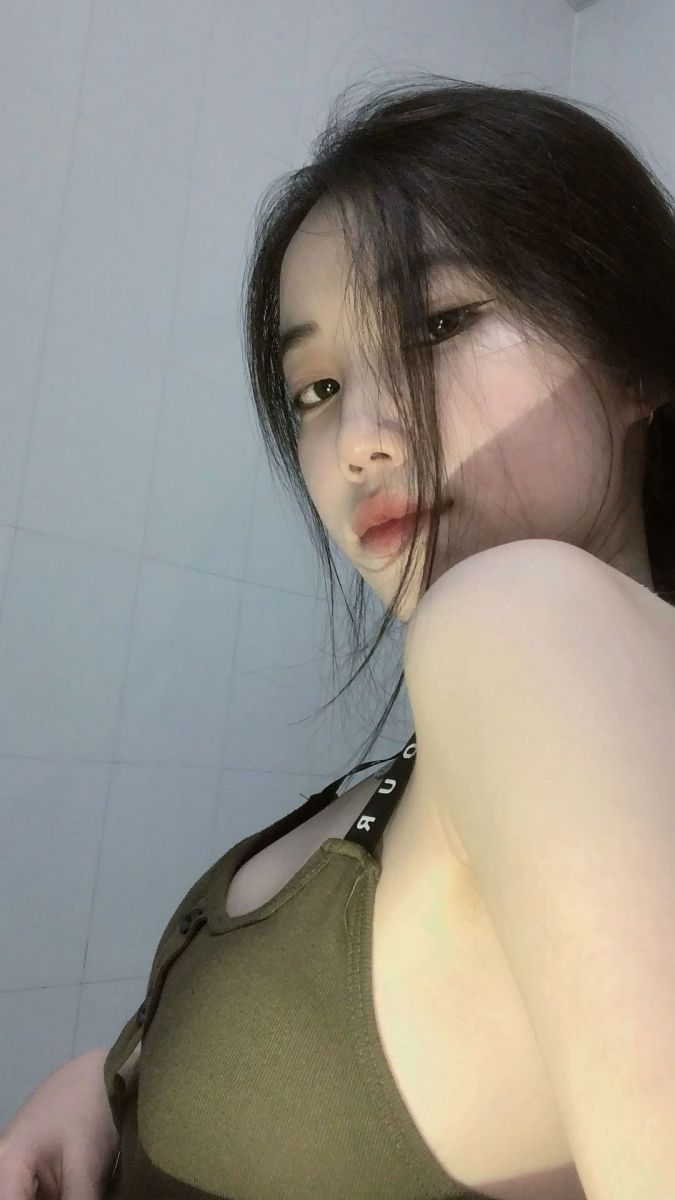 Ảnh gái trẻ mặc áo thun màu olive chụp ảnh trong không gian nhà