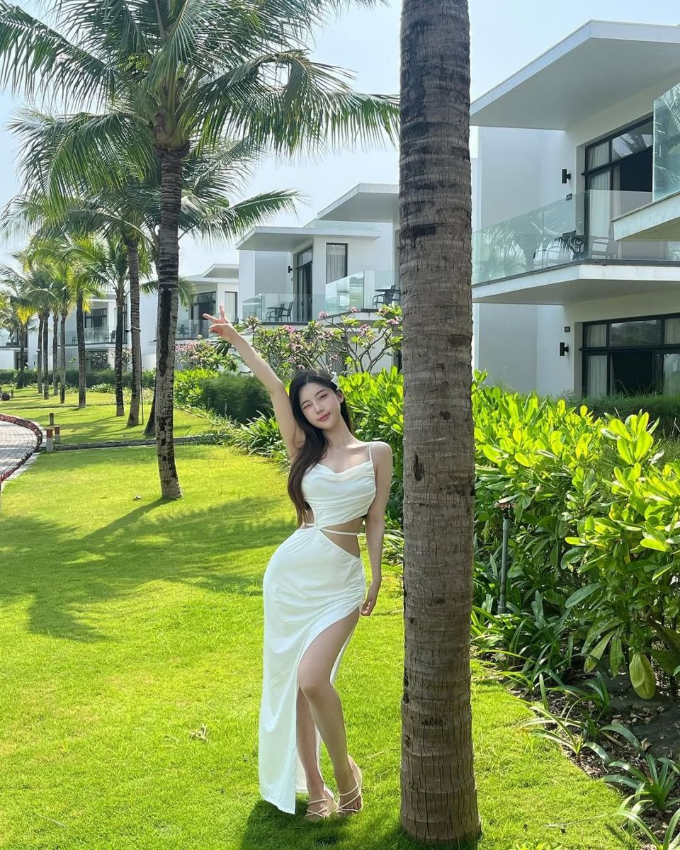 Ảnh gái trẻ mặc váy trắng bên cây dừa trong khu nghỉ dưỡng xanh mát