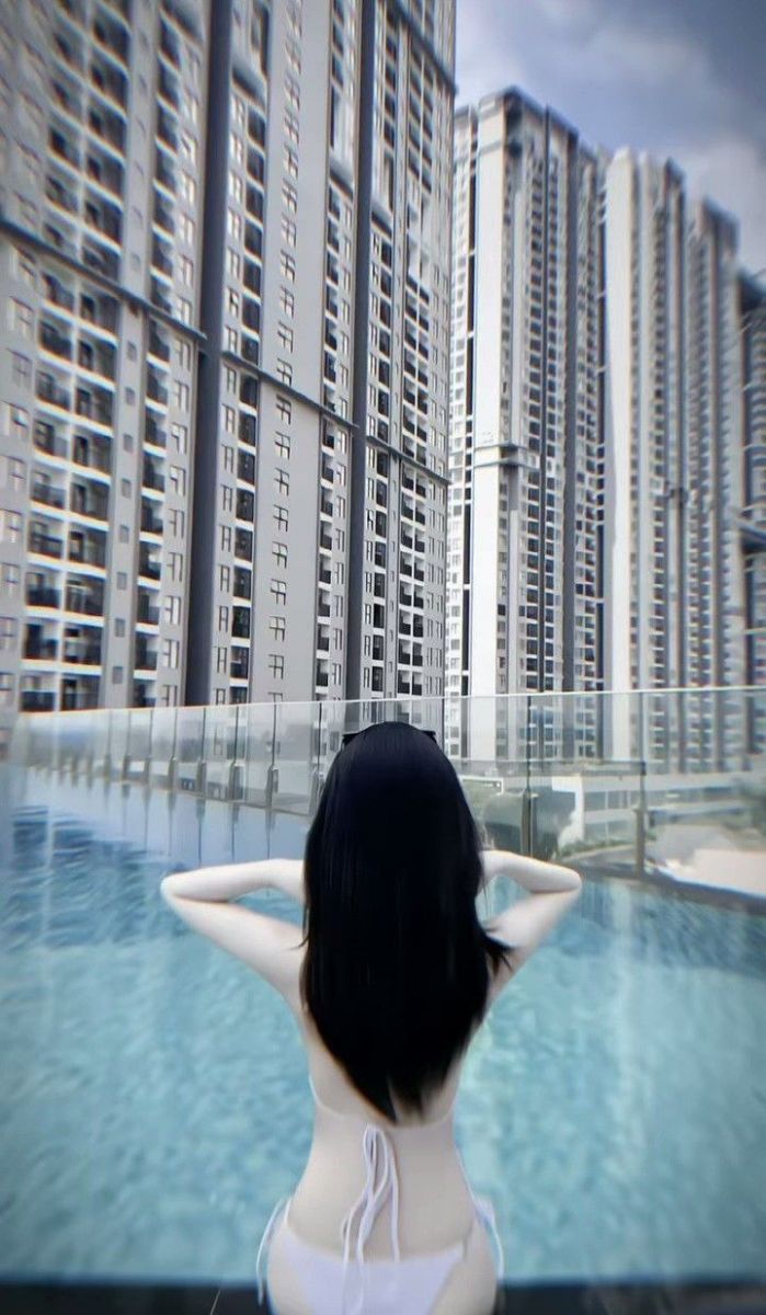 Cô gái bikini trắng bên bể bơi nhìn ra thành phố
