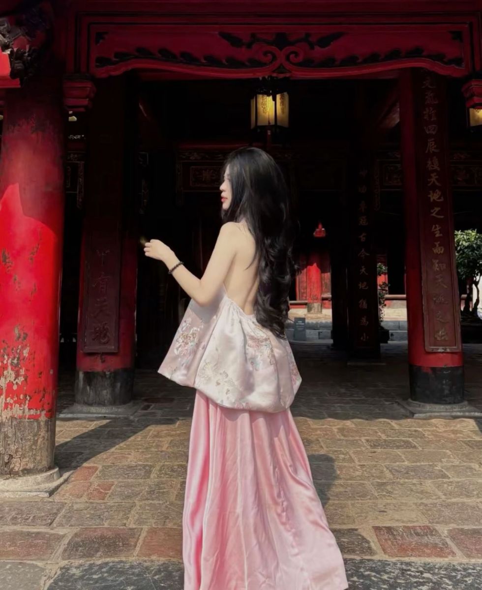 Cô gái đẹp mặc váy dài màu hồng tạo dáng tại nơi cổ kính