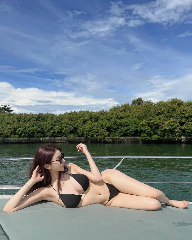 Cô gái mặc bikini đen thư giãn trên thuyền giữa thiên nhiên