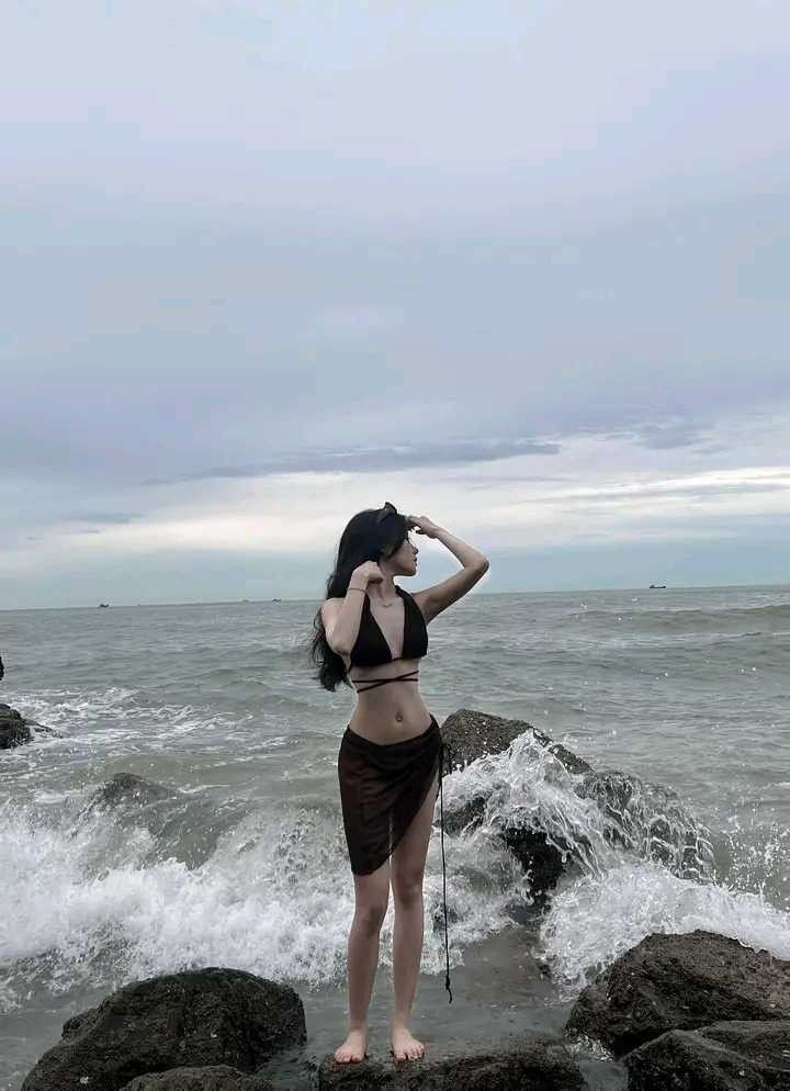 Cô gái mặc bikini màu đen và chân váy trên bãi biển Tây