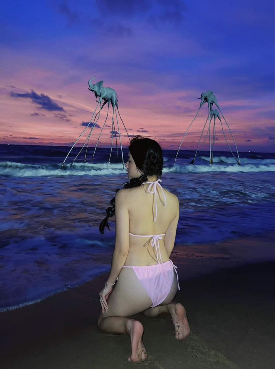 Cô gái trẻ mặc bikini màu hồng bên bờ biển ngắm hoàng hôn