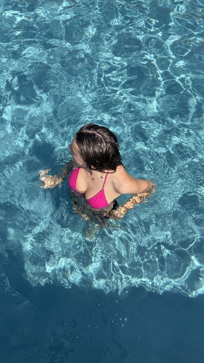 Cô gái trẻ mặc bikini màu hồng tươi vui bên hồ bơi