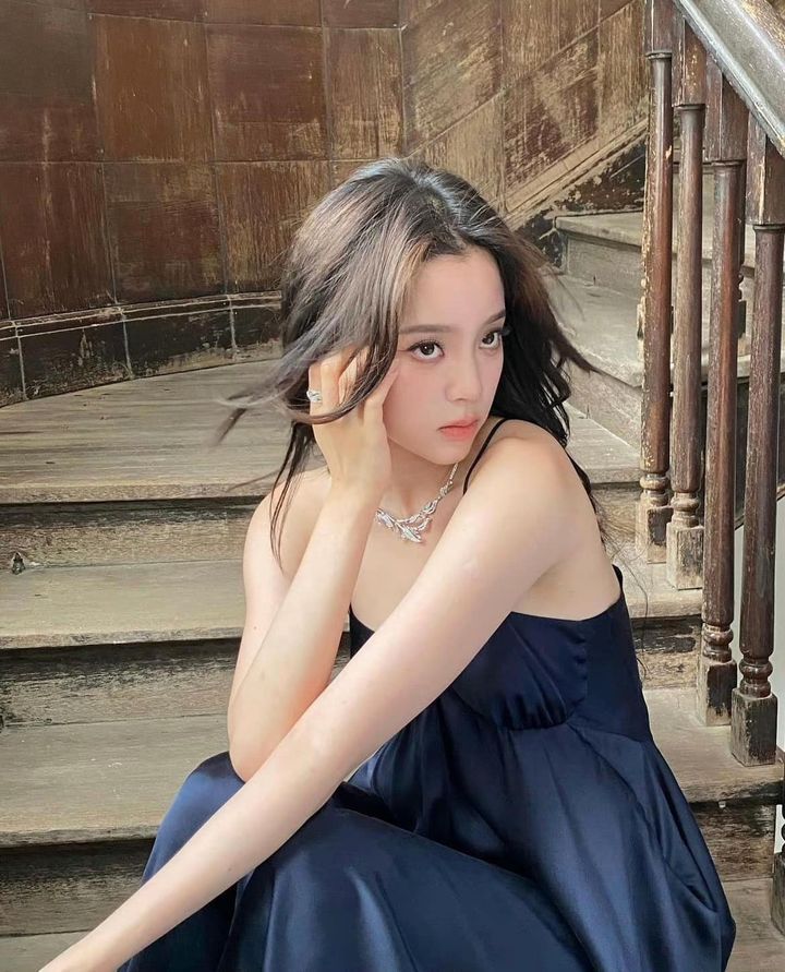 Cô gái trẻ mặc váy đen ngồi trên cầu thang gỗ