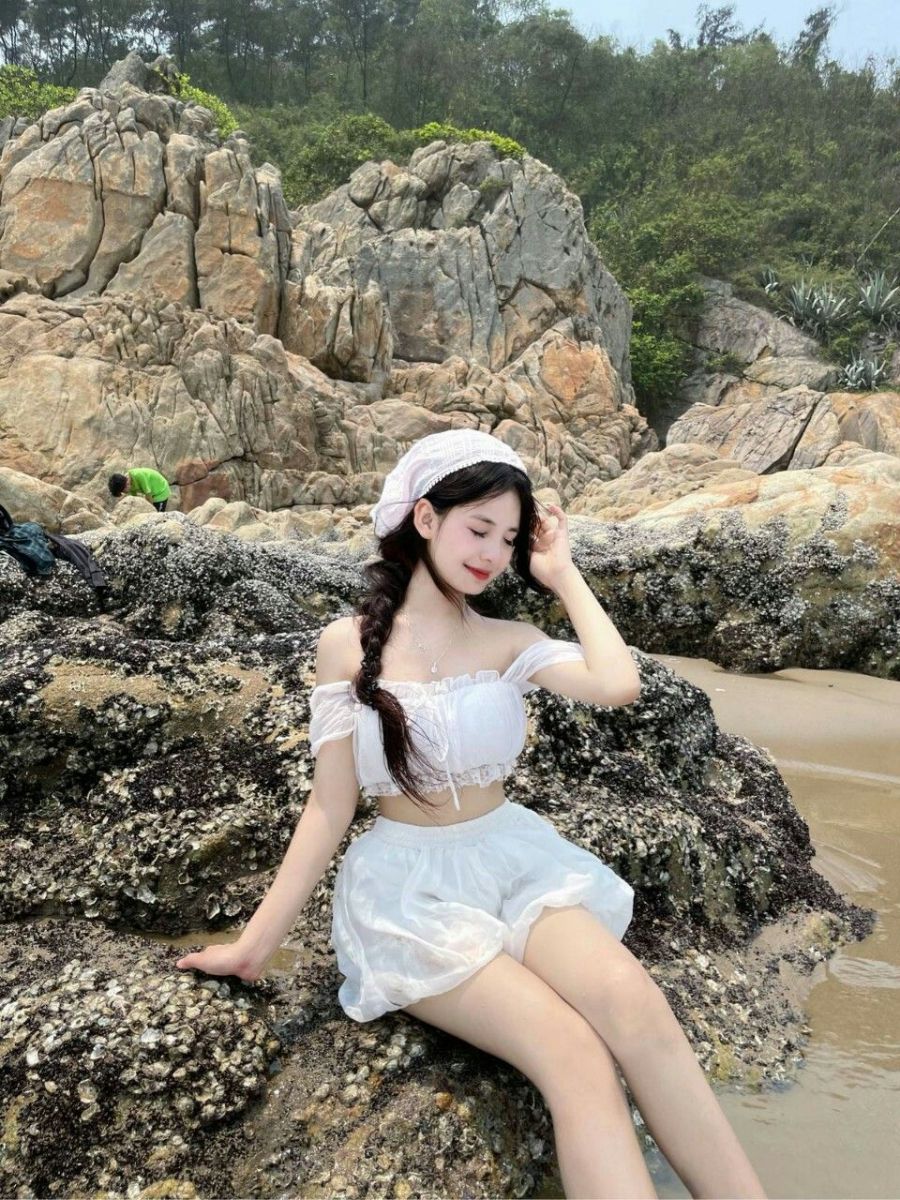 Cô gái trẻ xinh đẹp mặc áo crop top trắng và chân váy trắng