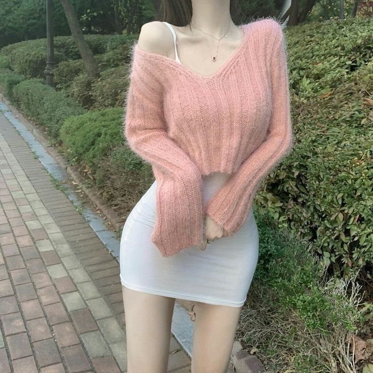 Cô gái trẻ xinh đẹp trong áo len hồng và váy trắng giữa khung cảnh xanh tươi