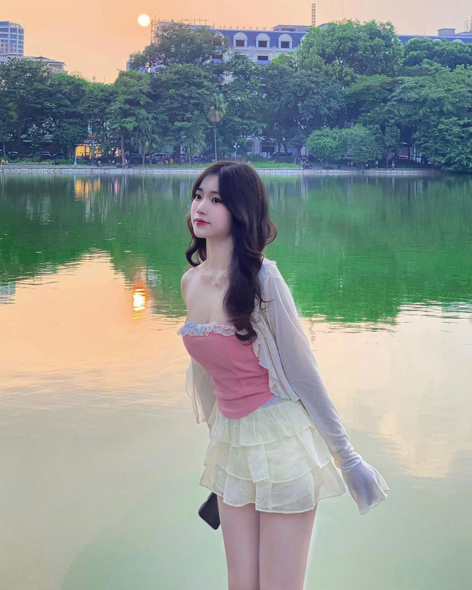 Cô gái xinh đẹp trong áo hai dây và váy xếp ly bên hồ Tây