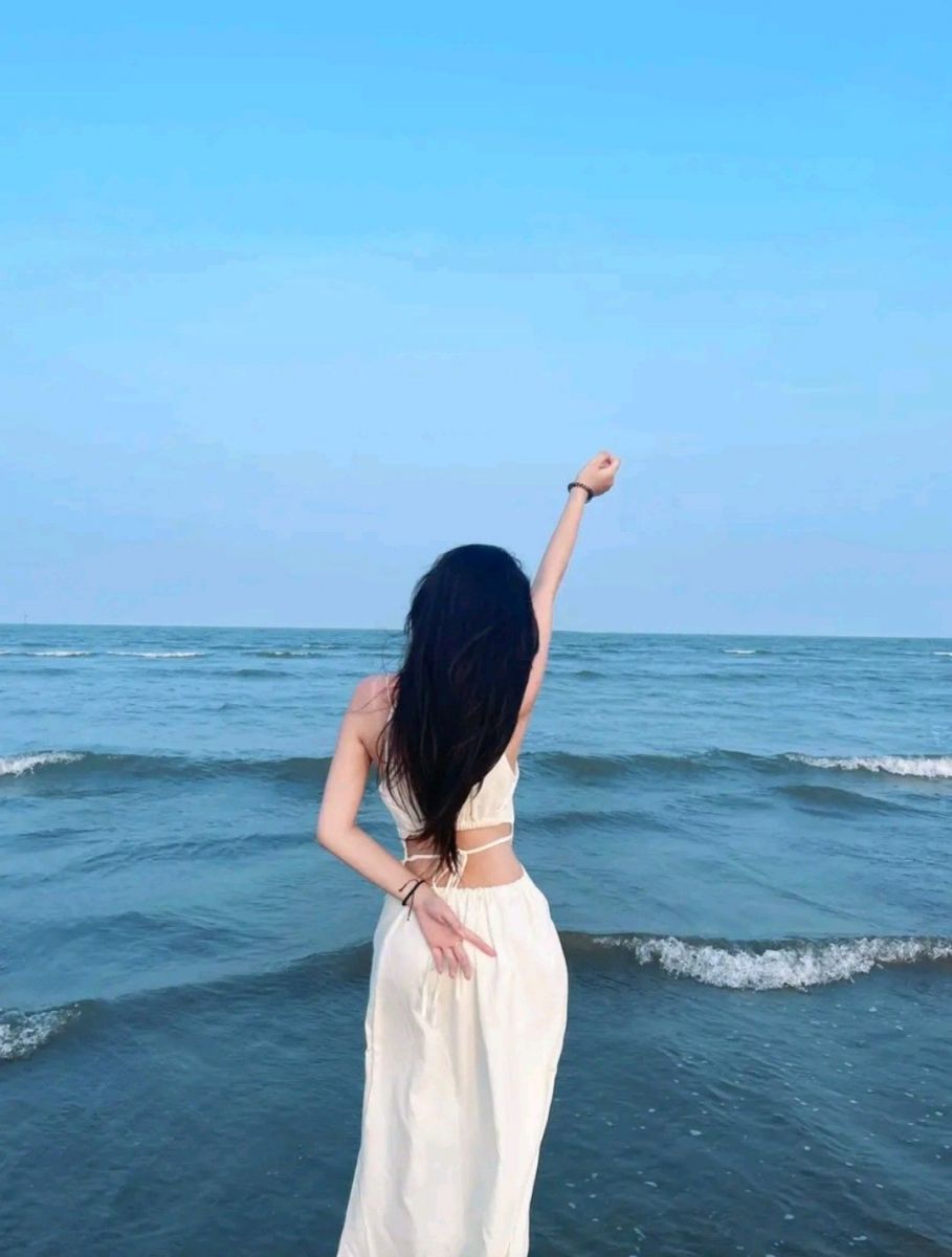 Cô gái xinh đẹp trong váy trắng bên bờ biển