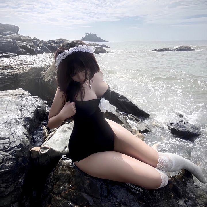 Gái đẹp mặc bikini đen ngồi trên đá ven biển