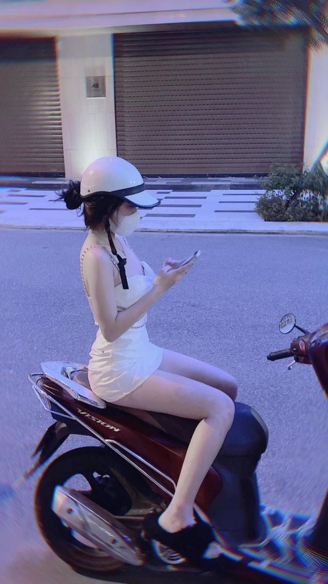 Gái đẹp mặc váy trắng ngồi trên xe máy vào buổi tối