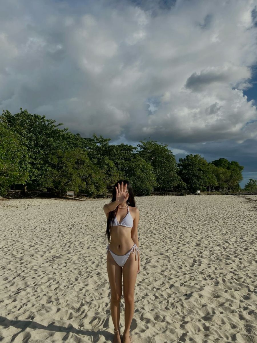 Gái xinh che mặt với bikini trắng trên bãi cát biển