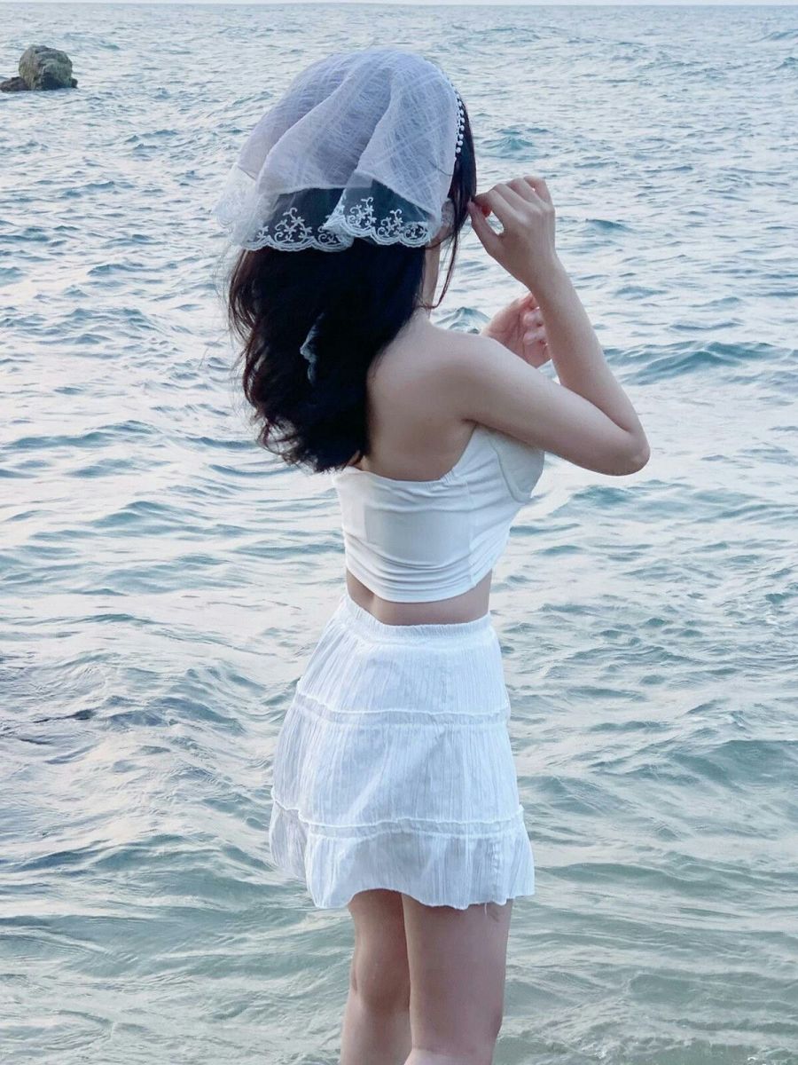 Gái xinh mặc áo crop top trắng và chân váy trắng bên bờ biển