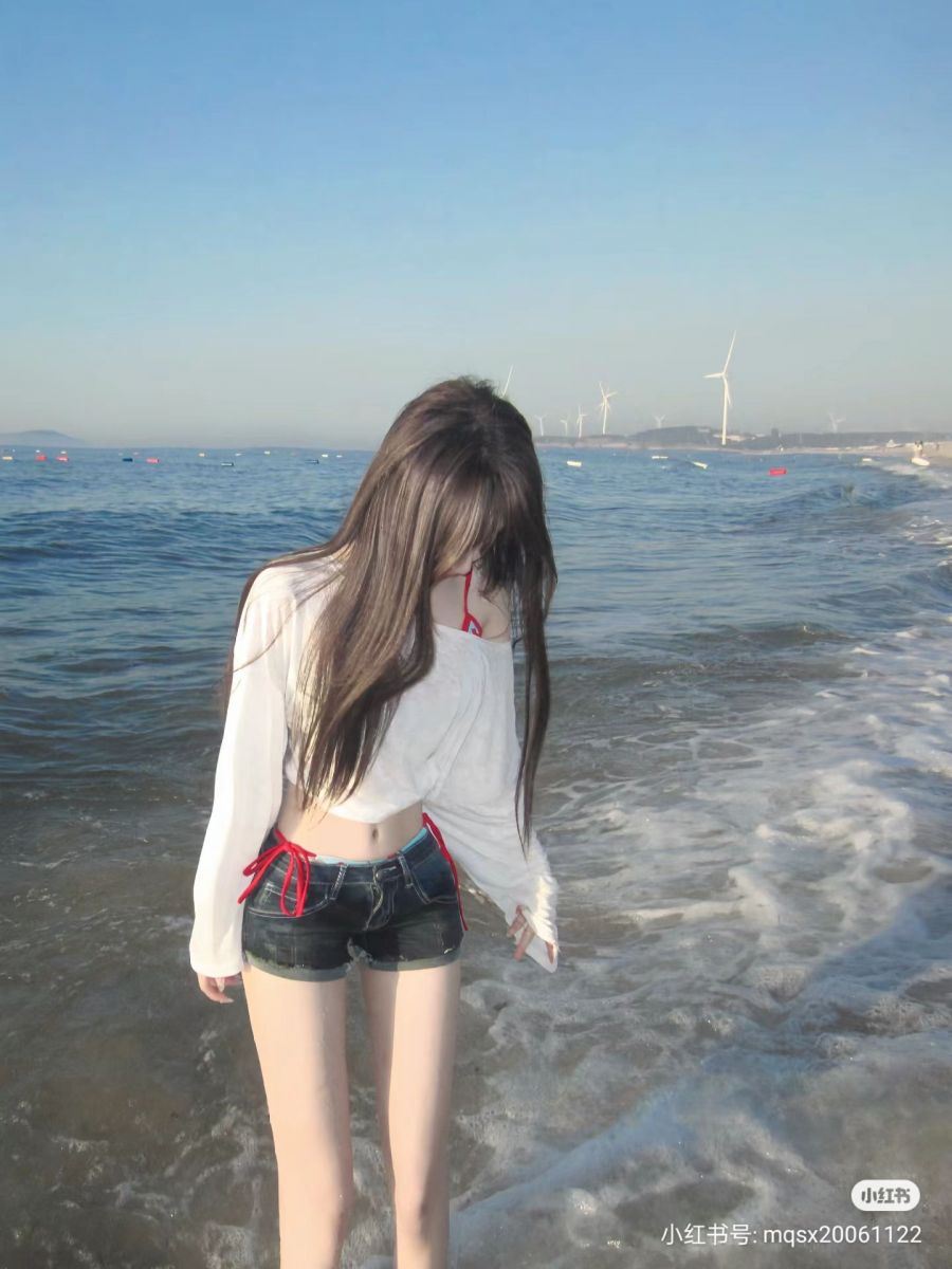 Gái xinh mặc áo dài trắng và quần short jeans trên bãi biển