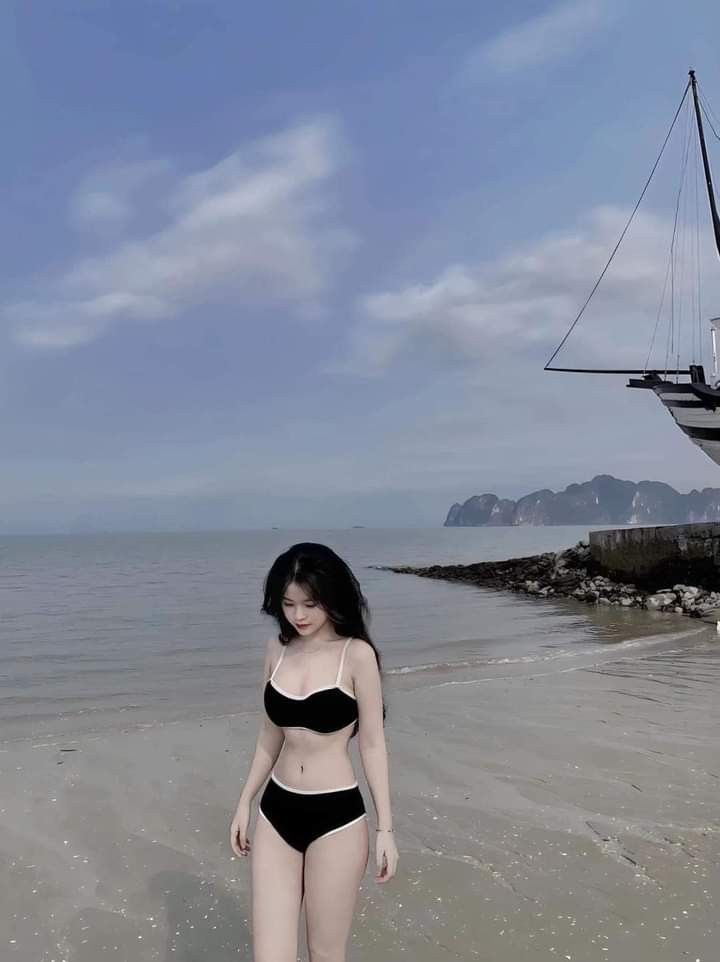 Gái xinh mặc bikini đen đứng trên bãi biển