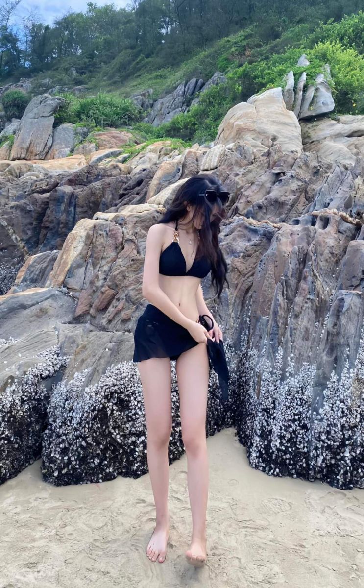 Gái xinh mặc bikini đen và váy ngắn trên bãi biển