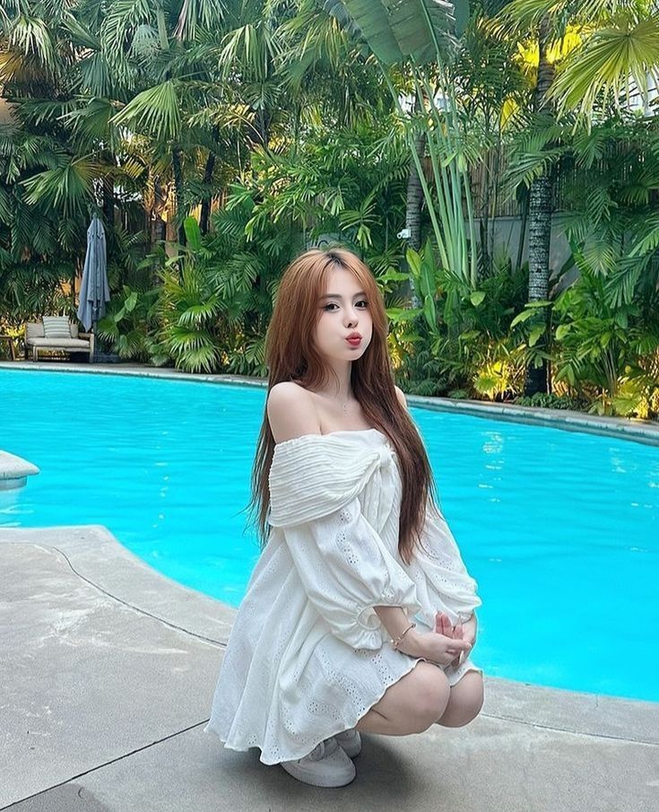 Gái xinh mặc váy trắng bên bể bơi xanh