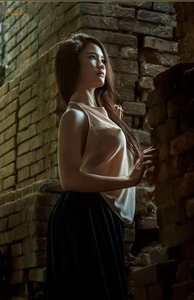 Gái xinh mặc váy trắng tạo dáng bên tường gạch cổ điển