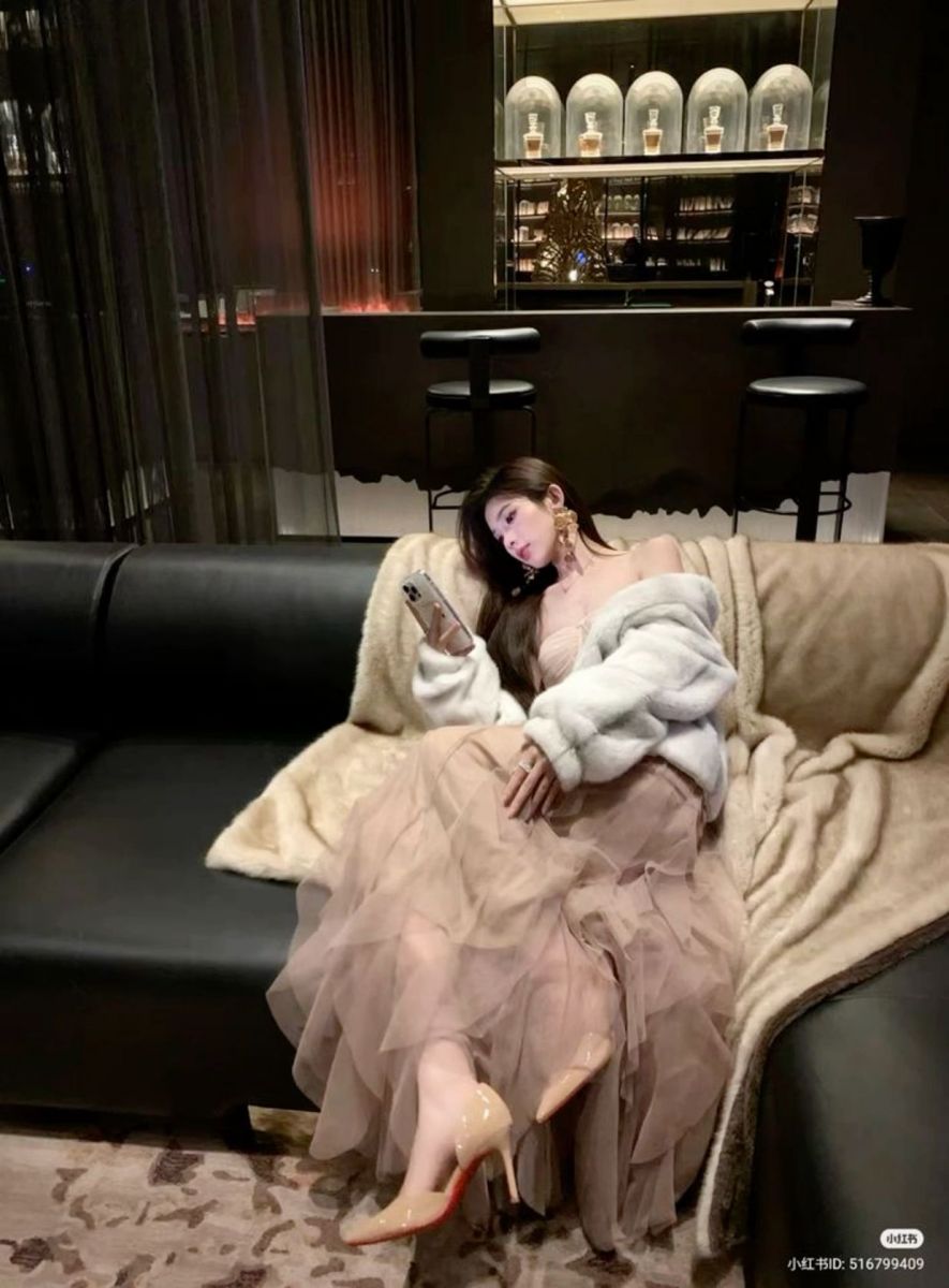 Gái xinh mặc váy trắng và áo choàng lông trên ghế sofa
