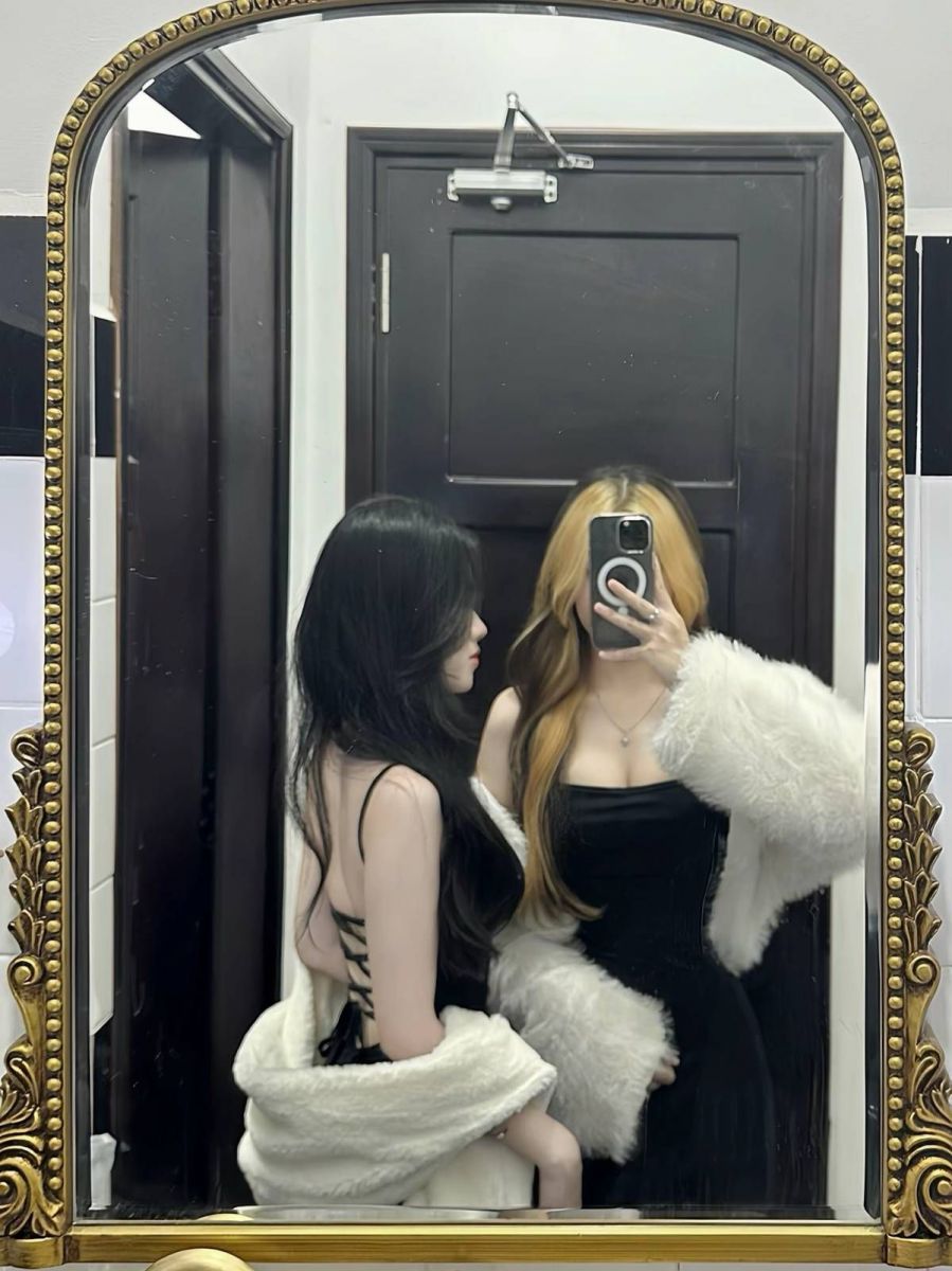 Hai cô gái mặc áo đầm đen và trắng chụp ảnh tạo dáng