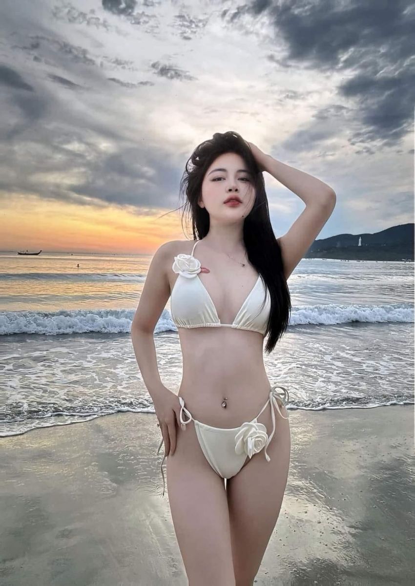 Nữ mặc bikini trắng dạo chơi trên bãi biển hoàng hôn lãng mạn